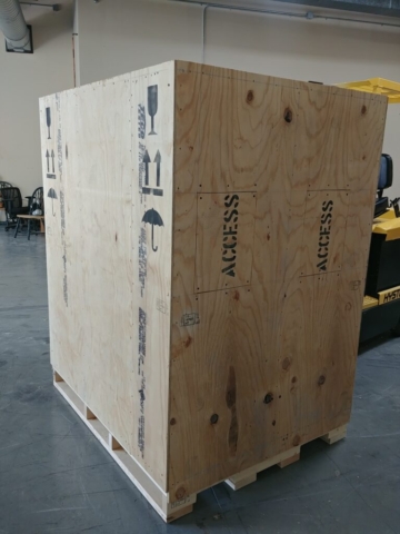 Export crates being manufactured in a workshop in Fairport, NY, with workers assembling sturdy wooden crates for international shipping. ISPM certified
